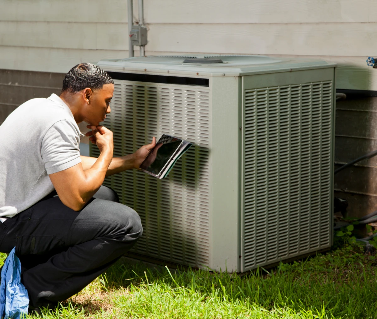 Man checking air conditioner with tablet.