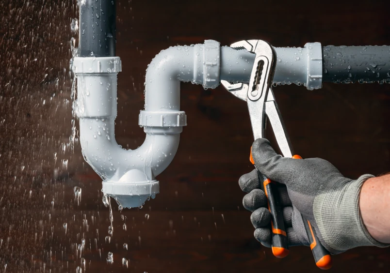 Hand repairing leaky pipe with pliers